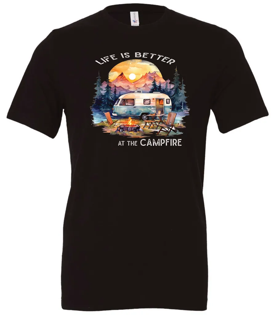 black campfire t-shirt featuring a camper by the lake, campfire on, and mountains with a sunset in the background, and it says life is better at the campfire.
