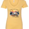 yellow campfire v-neck t-shirt featuring a camper by the lake, campfire on, and mountains with a sunset in the background, and it says life is better at the campfire.