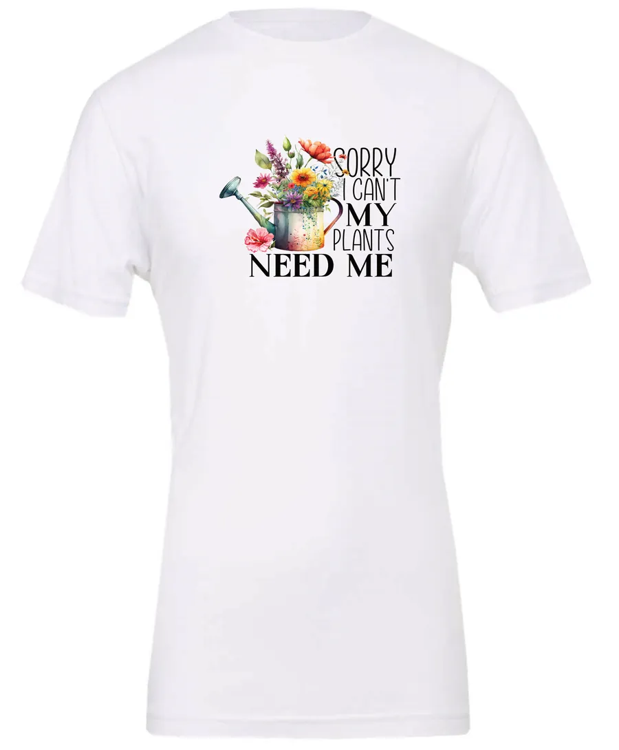 white garden humor t-shirt with a watering can used as a flower pot, it has many different flowers and a quote saying sorry i can't, my plants need me